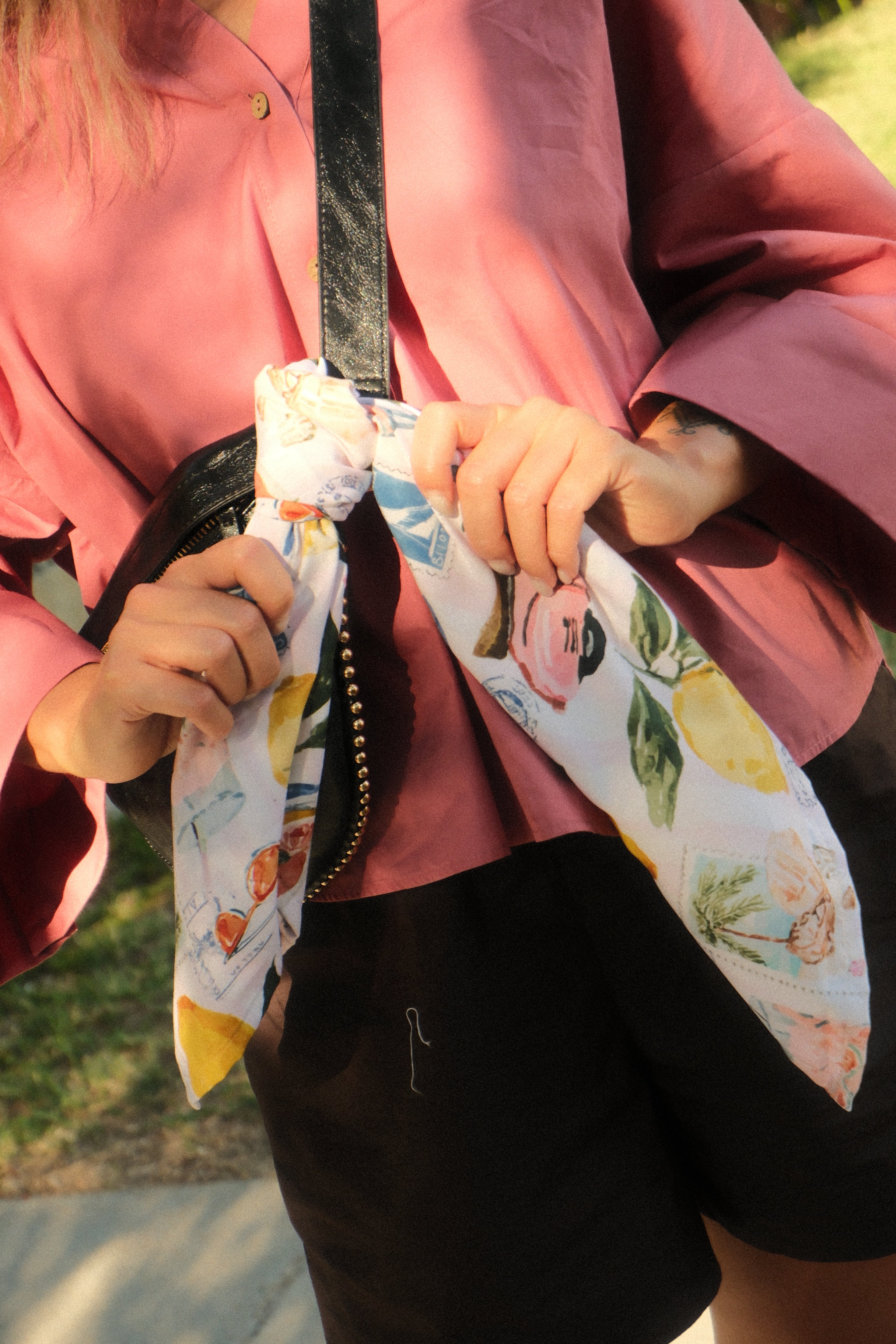 Person holding a colorful umbrella with floral design, wearing a pink garment.