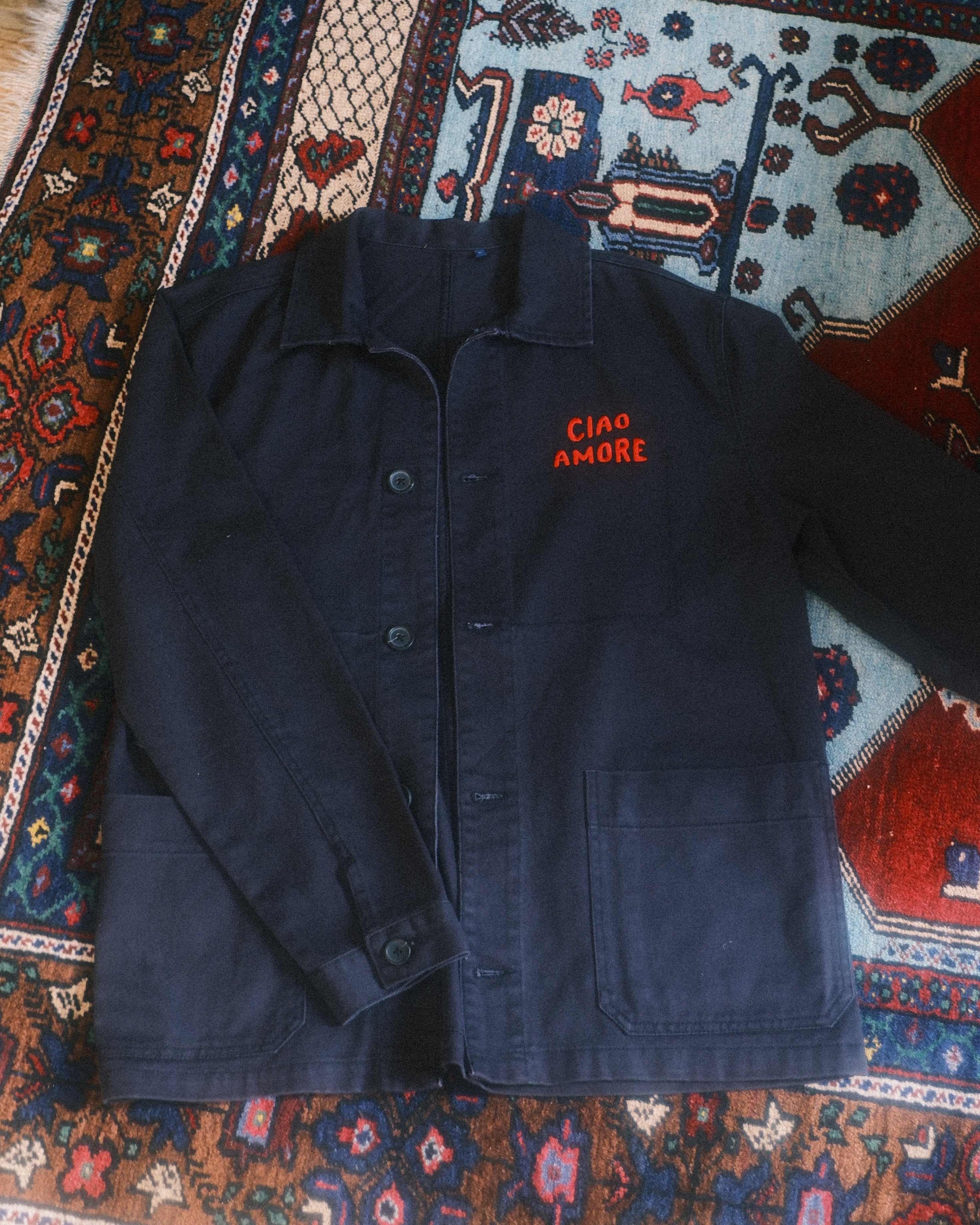 Dark blue jacket with red text on a patterned rug