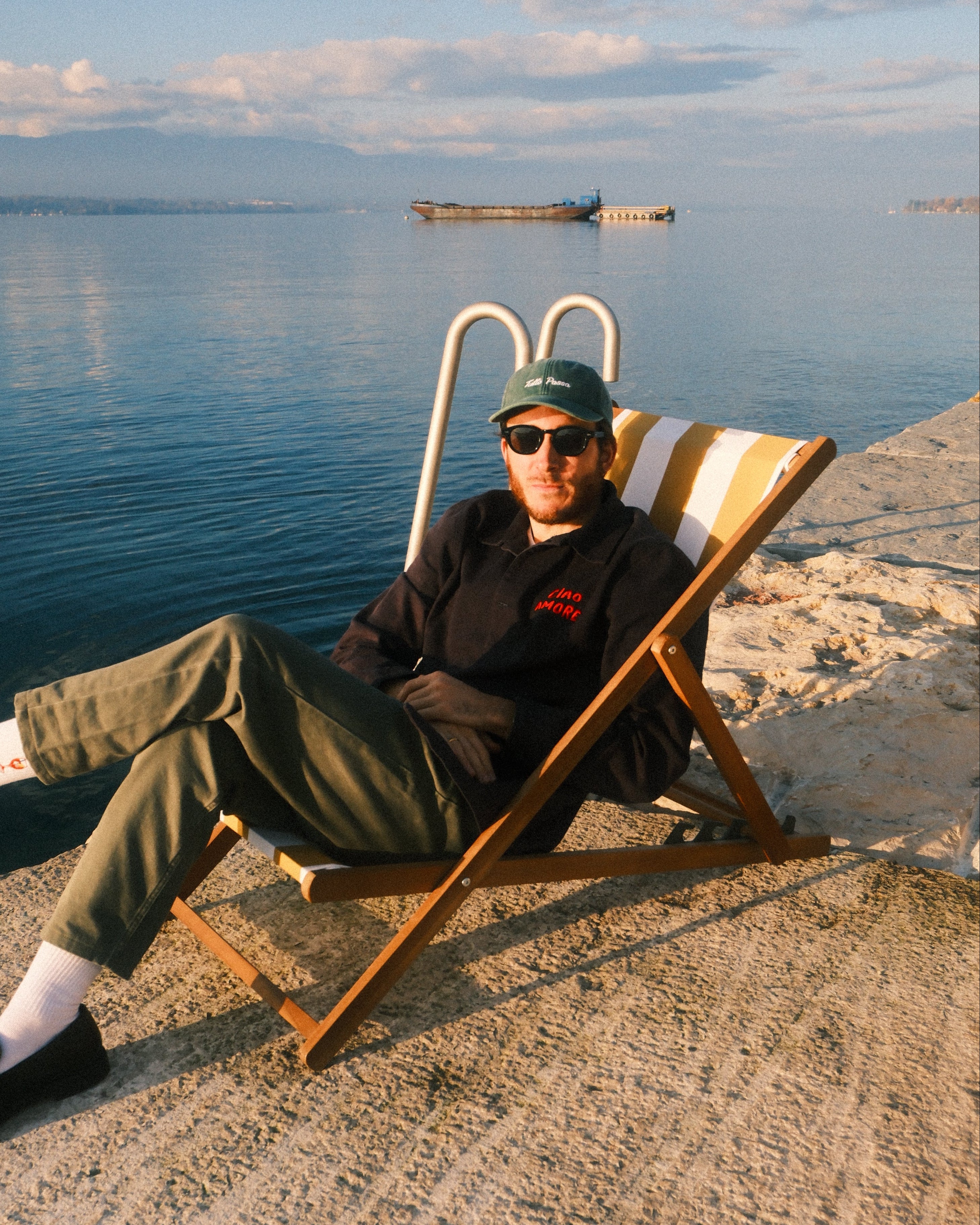 Person lying on a small cart with a blue sky and water in the background