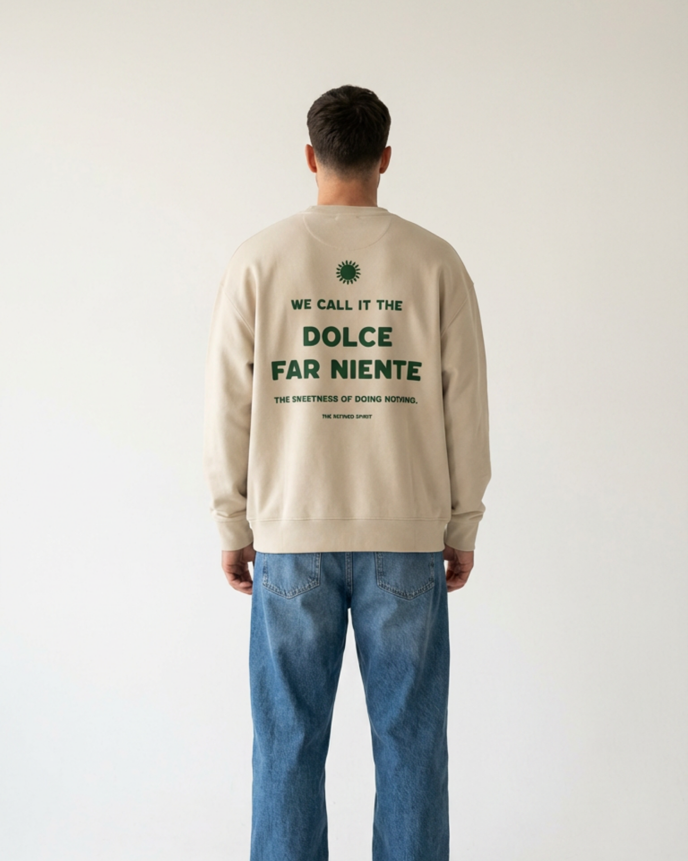 Person wearing a beige sweatshirt with text on the back, standing against a plain background