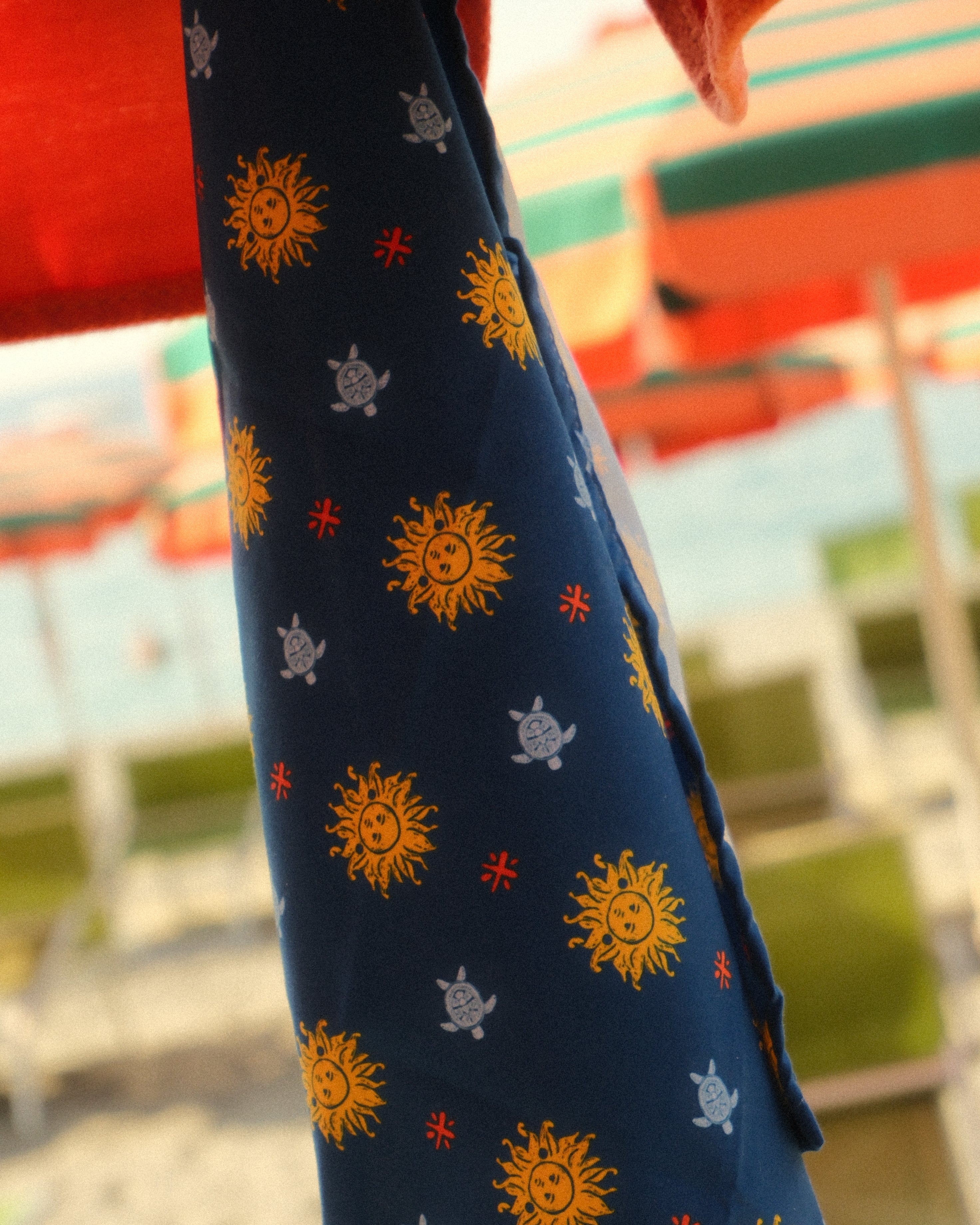 Navy blue fabric with sun and star patterns held by a person against a blurred outdoor background.