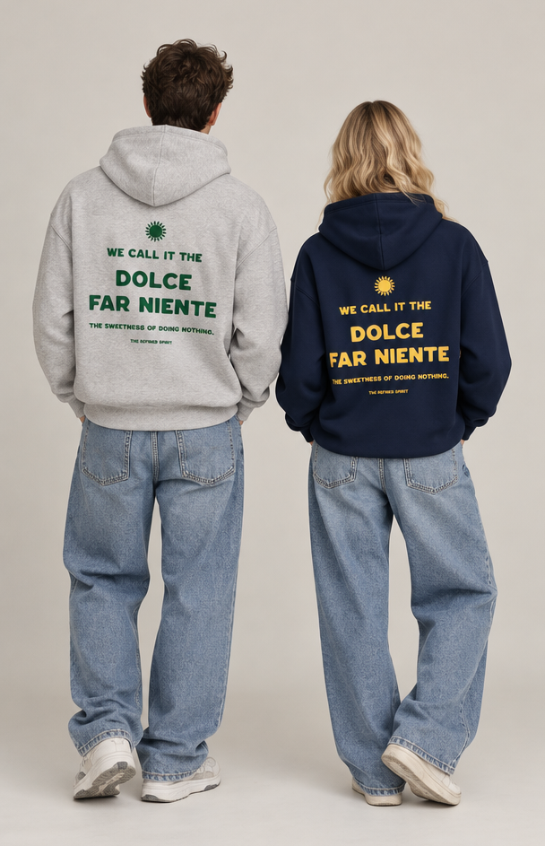 Two models from behind wearing oversized hoodies with 'DOLCE FAR NIENTE' text on the back, one in light gray and one in navy blue, paired with light-wash jeans, against a plain light gray studio background.