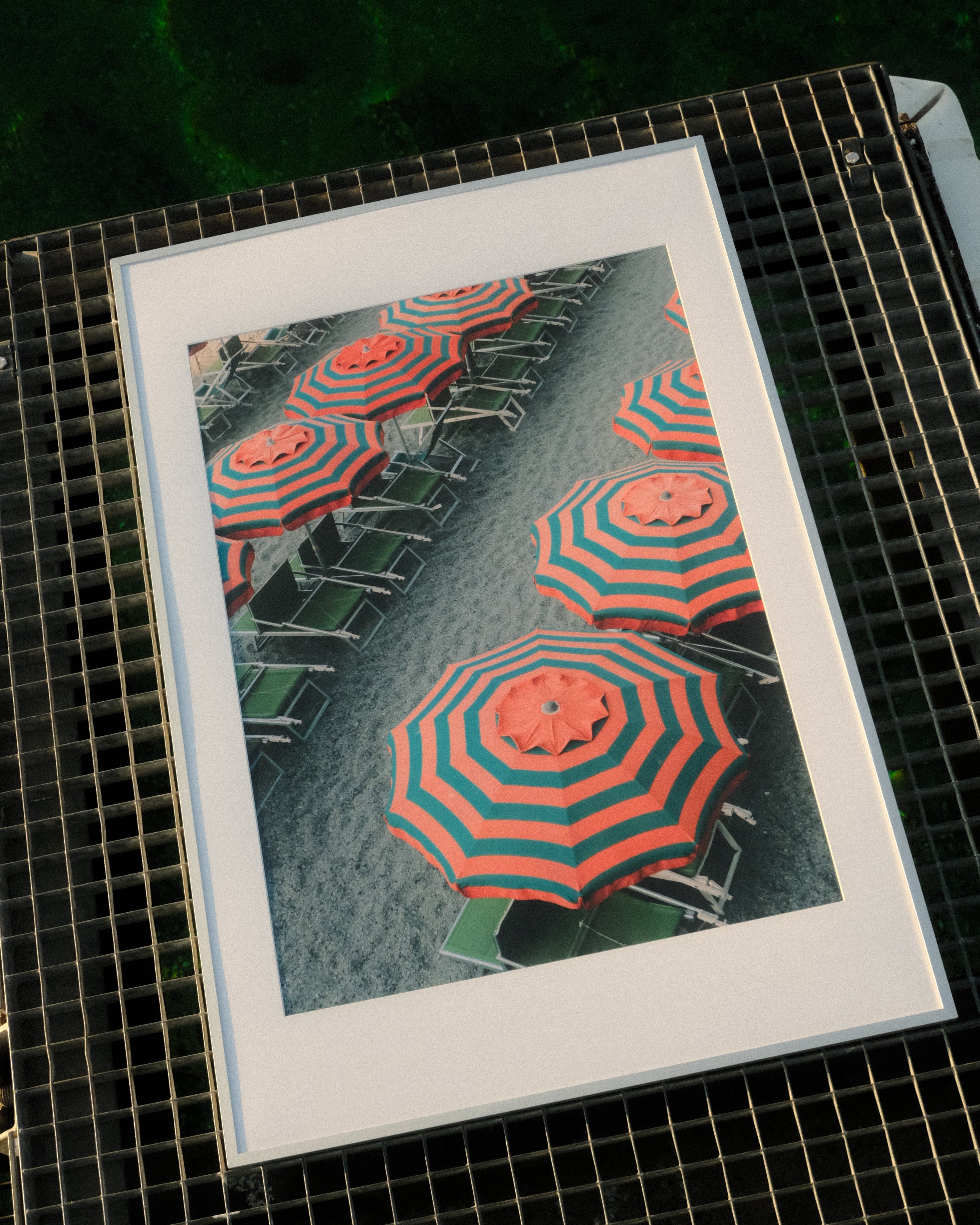 Framed artwork of red and green striped umbrellas on a tiled floor.