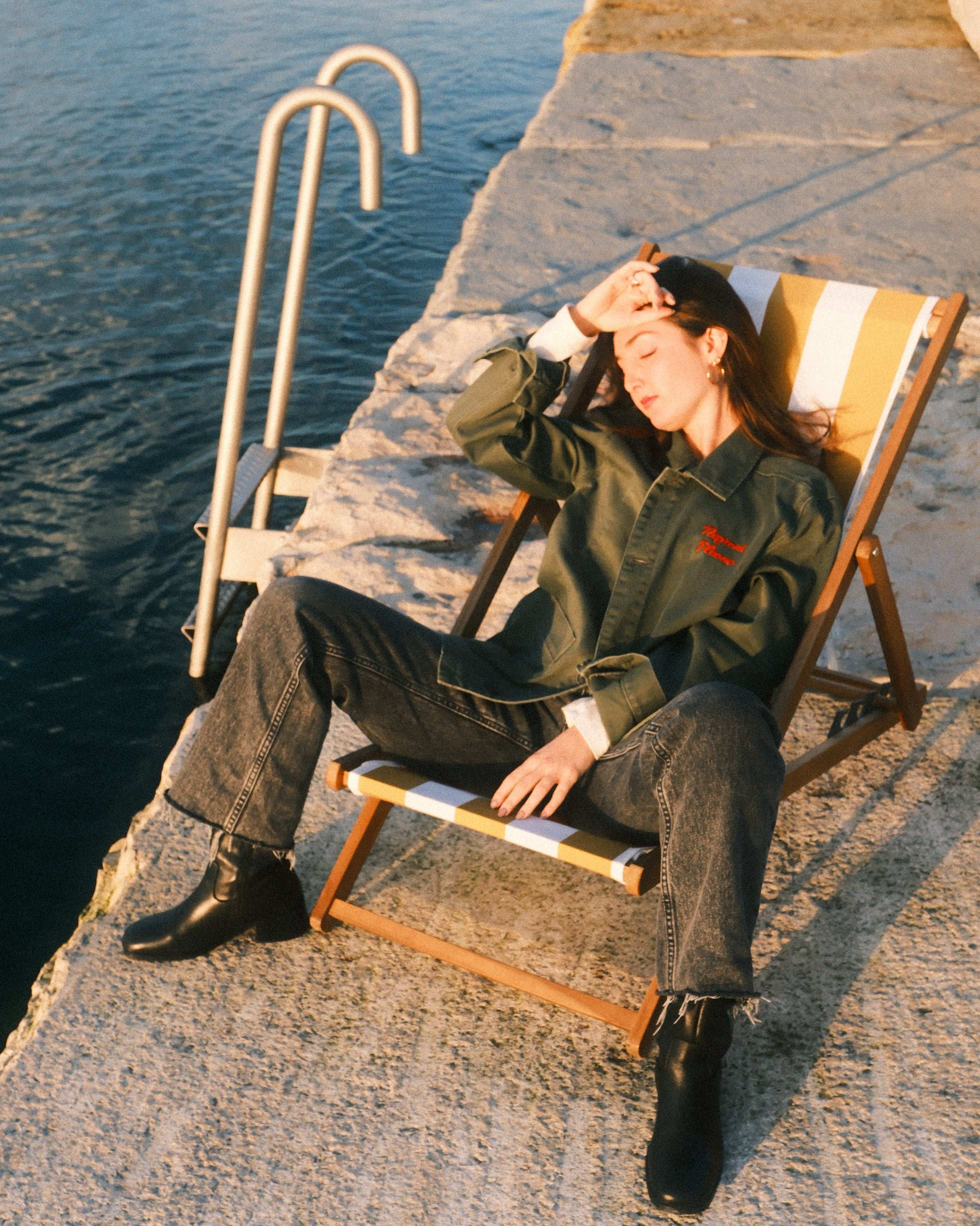 Person lying on a sun lounger by a body of water