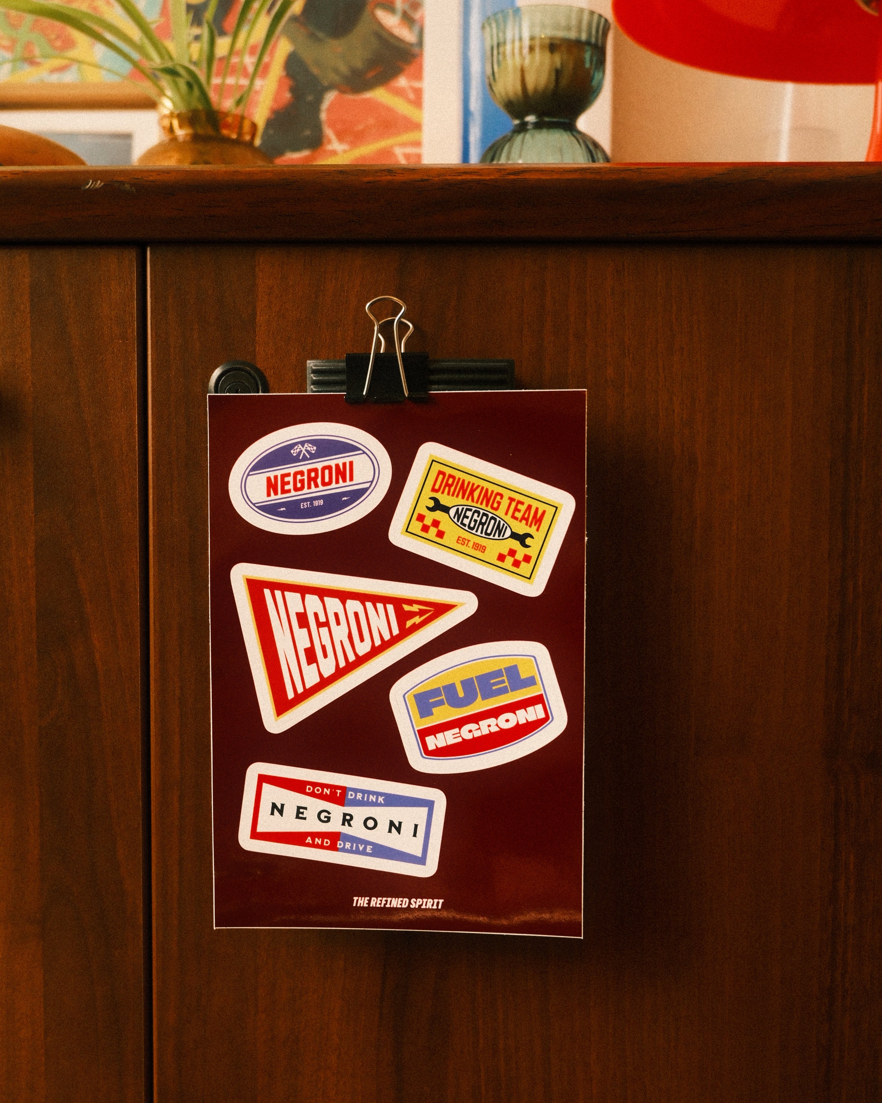Collection of vintage-style stickers on a brown paper bag with a clip, against a wooden surface.