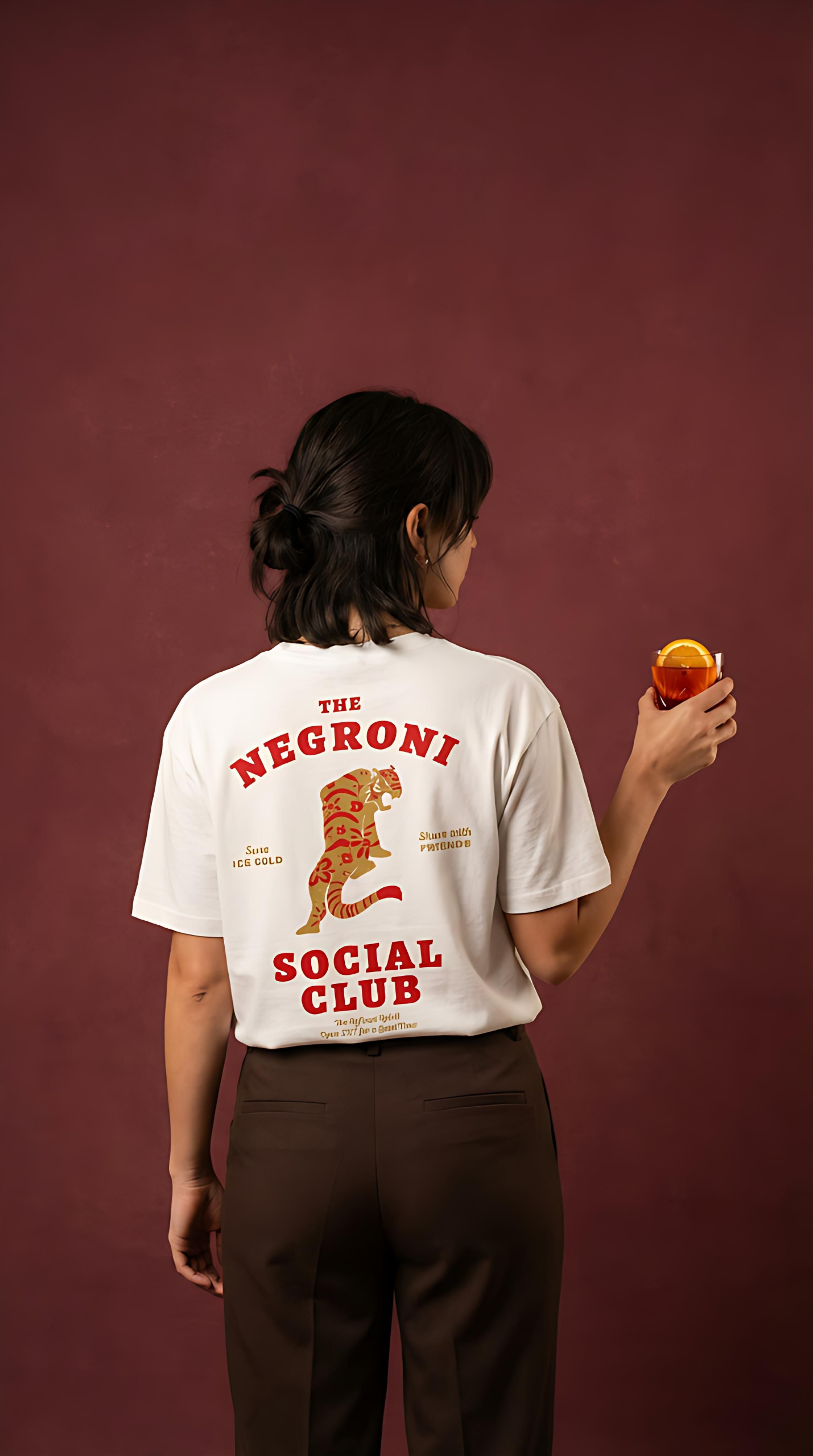 Person wearing a 'The Negroni Social Club' t-shirt against a maroon background