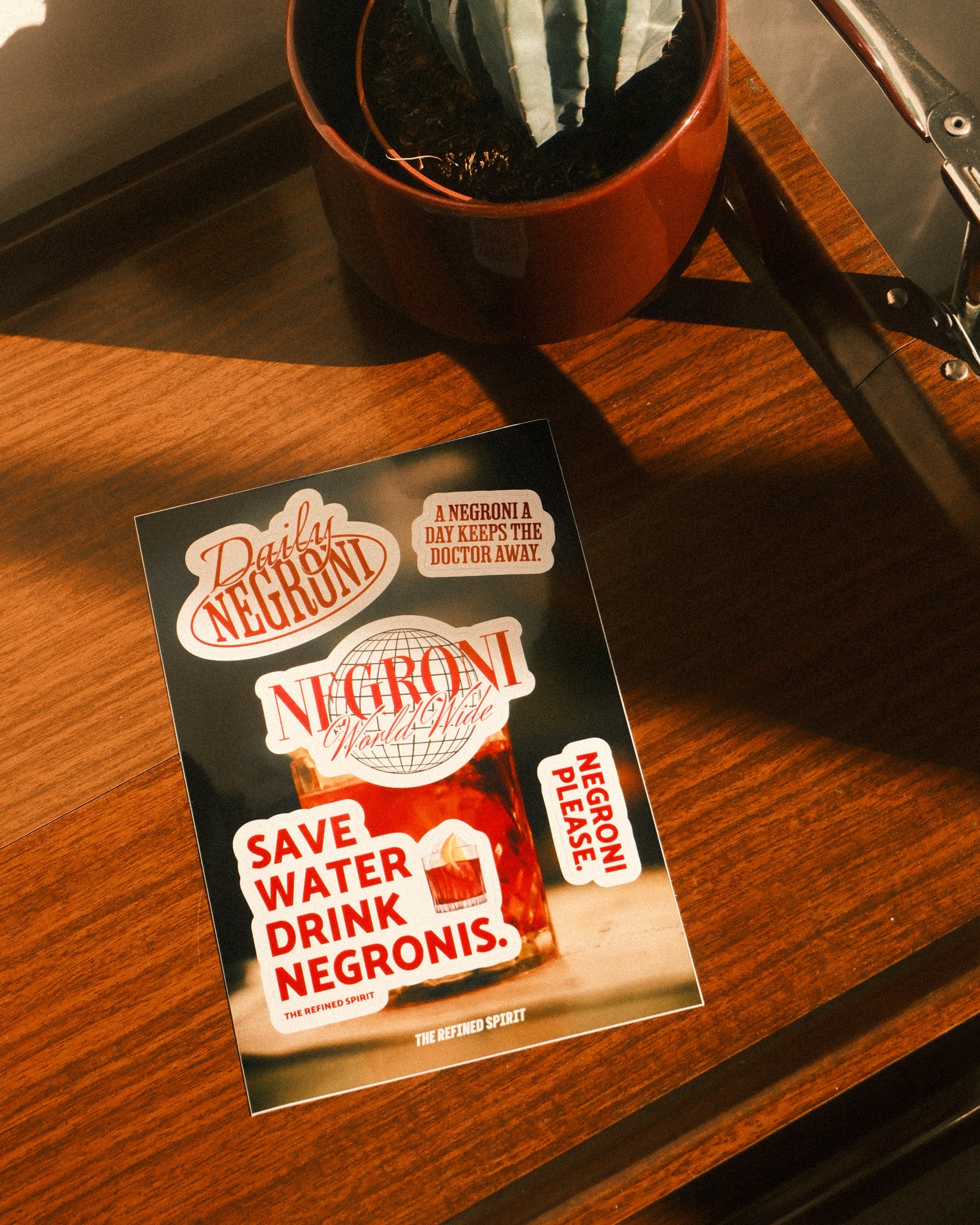 Packaging of Negroni cocktail with a plant on a wooden surface