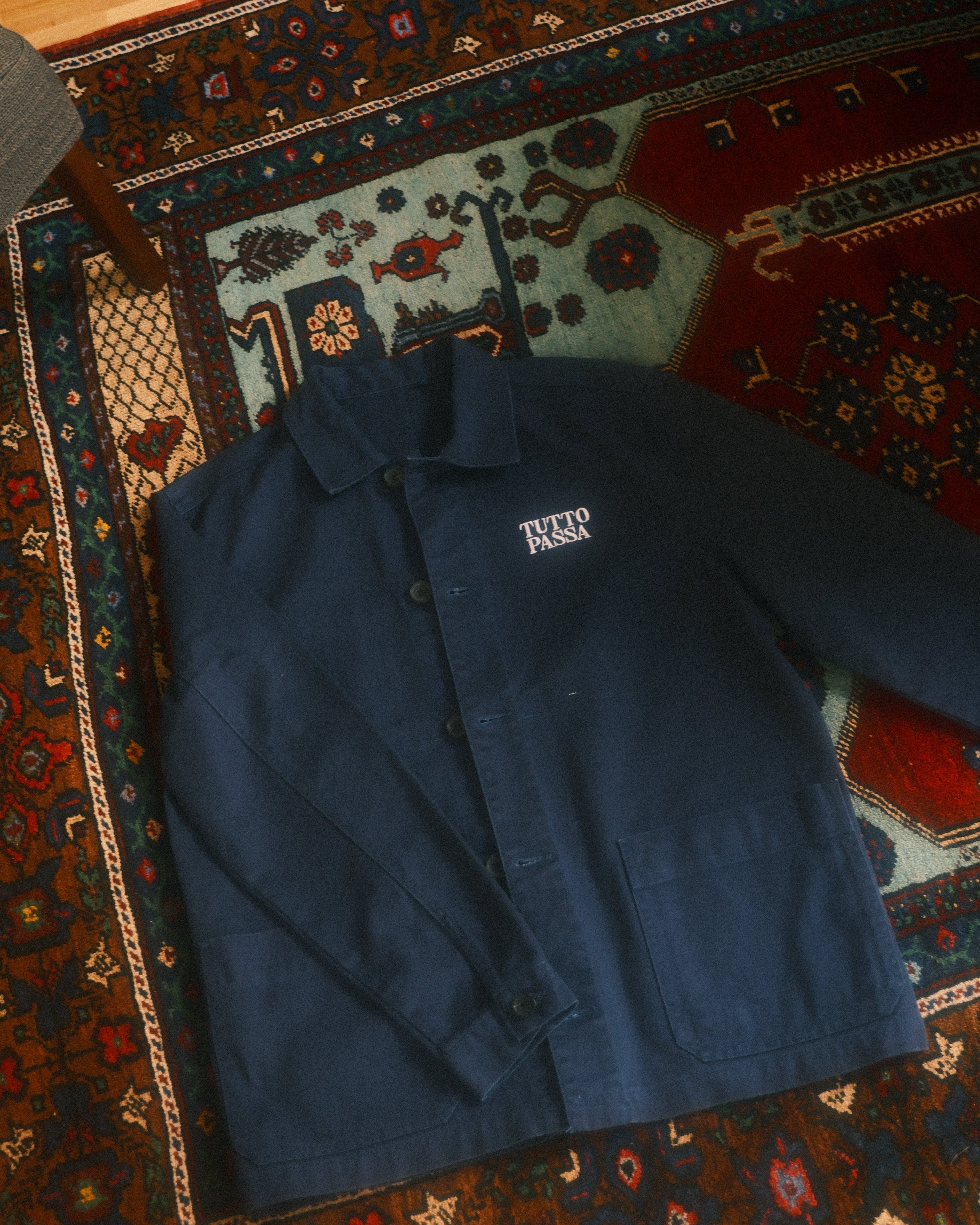 Blue jacket with a brand logo on a patterned rug