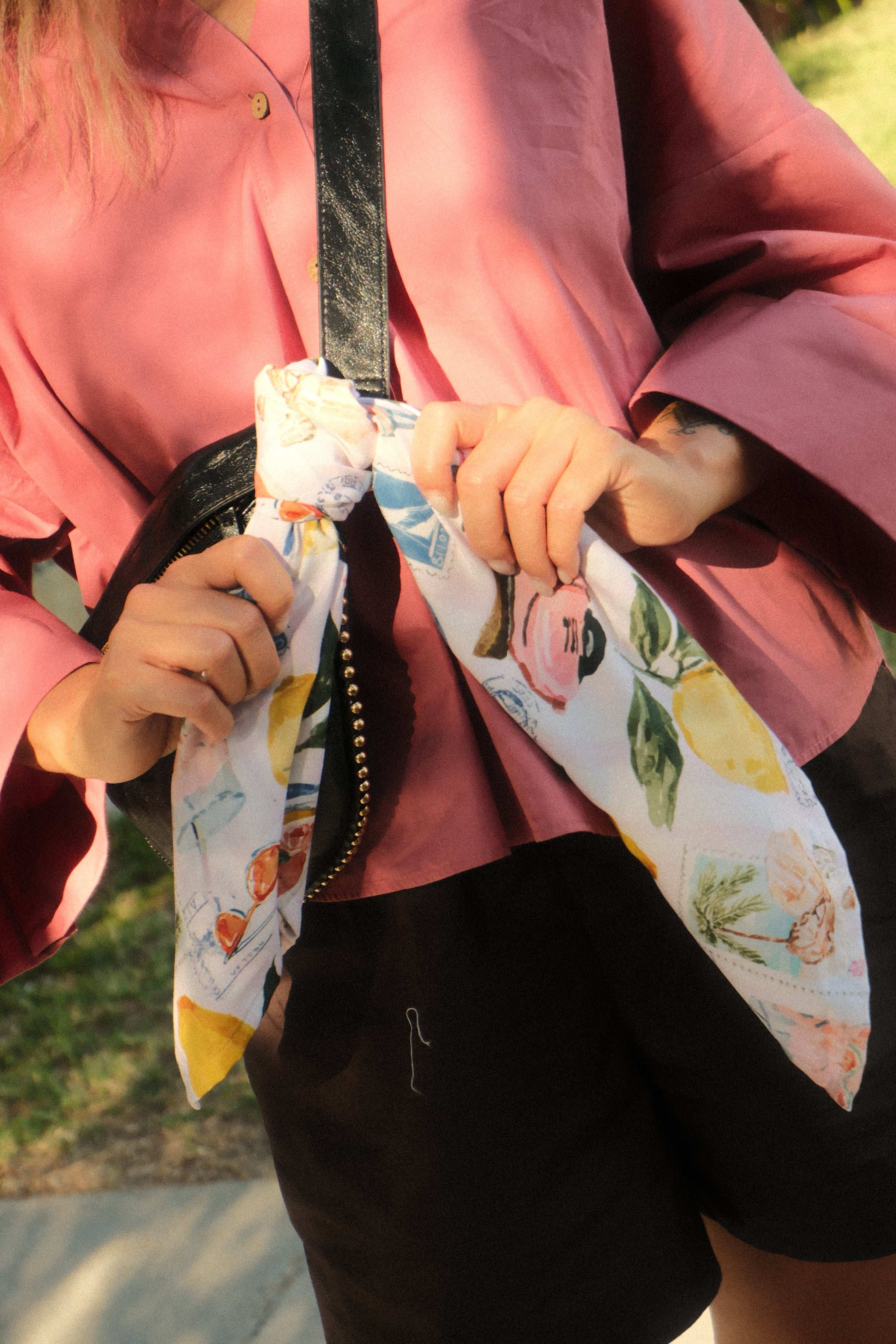 Person holding a colorful umbrella with floral design, wearing a pink garment.