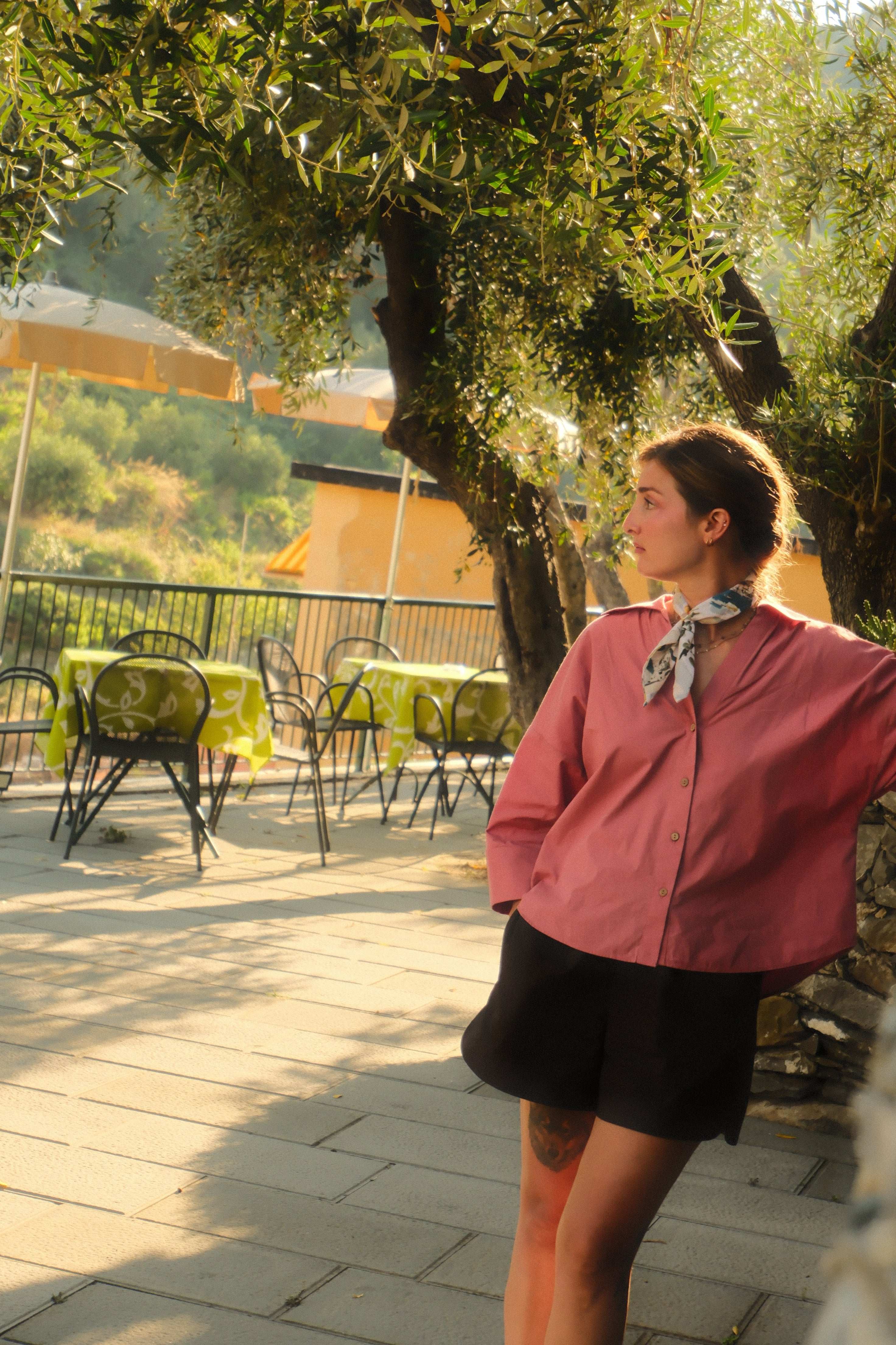 Person lying on a wooden deck with outdoor furniture and greenery in the background