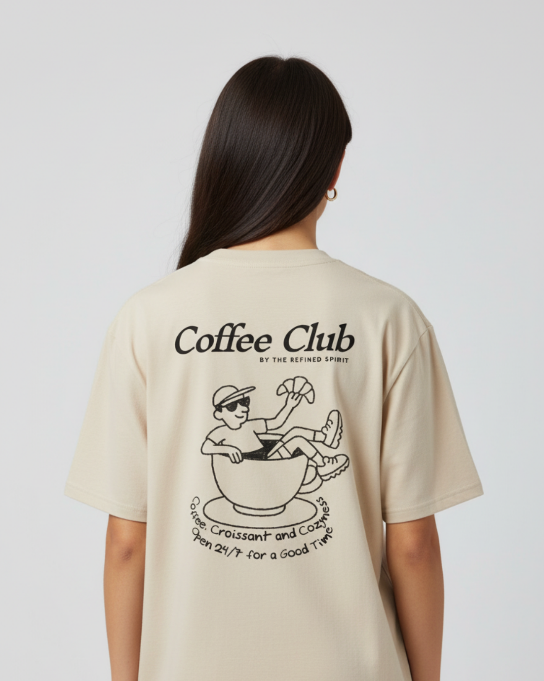 Person wearing a beige t-shirt with 'Coffee Club' graphic on the back