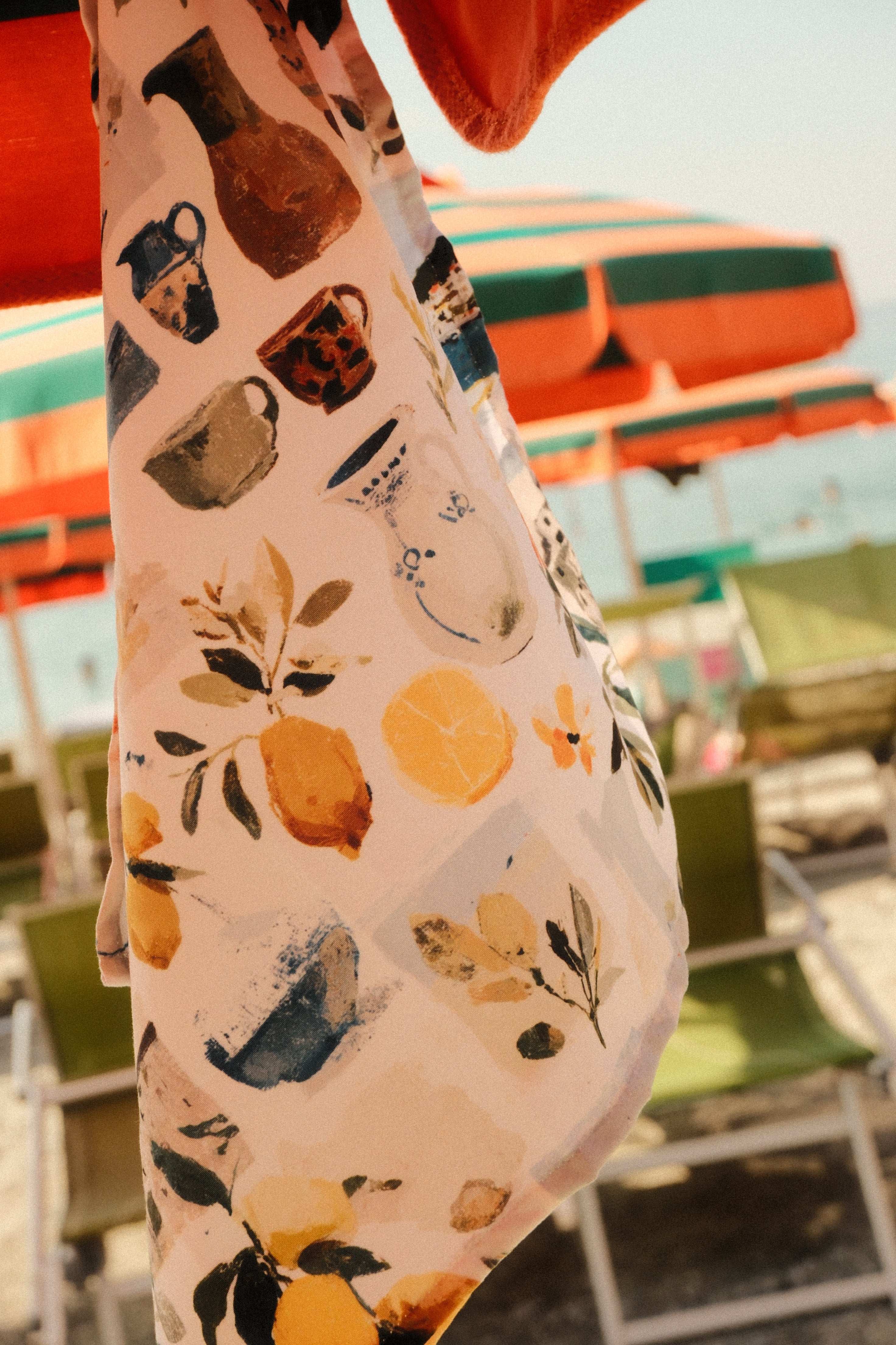 Fabric with cat and lemon pattern held up against a blurred indoor background