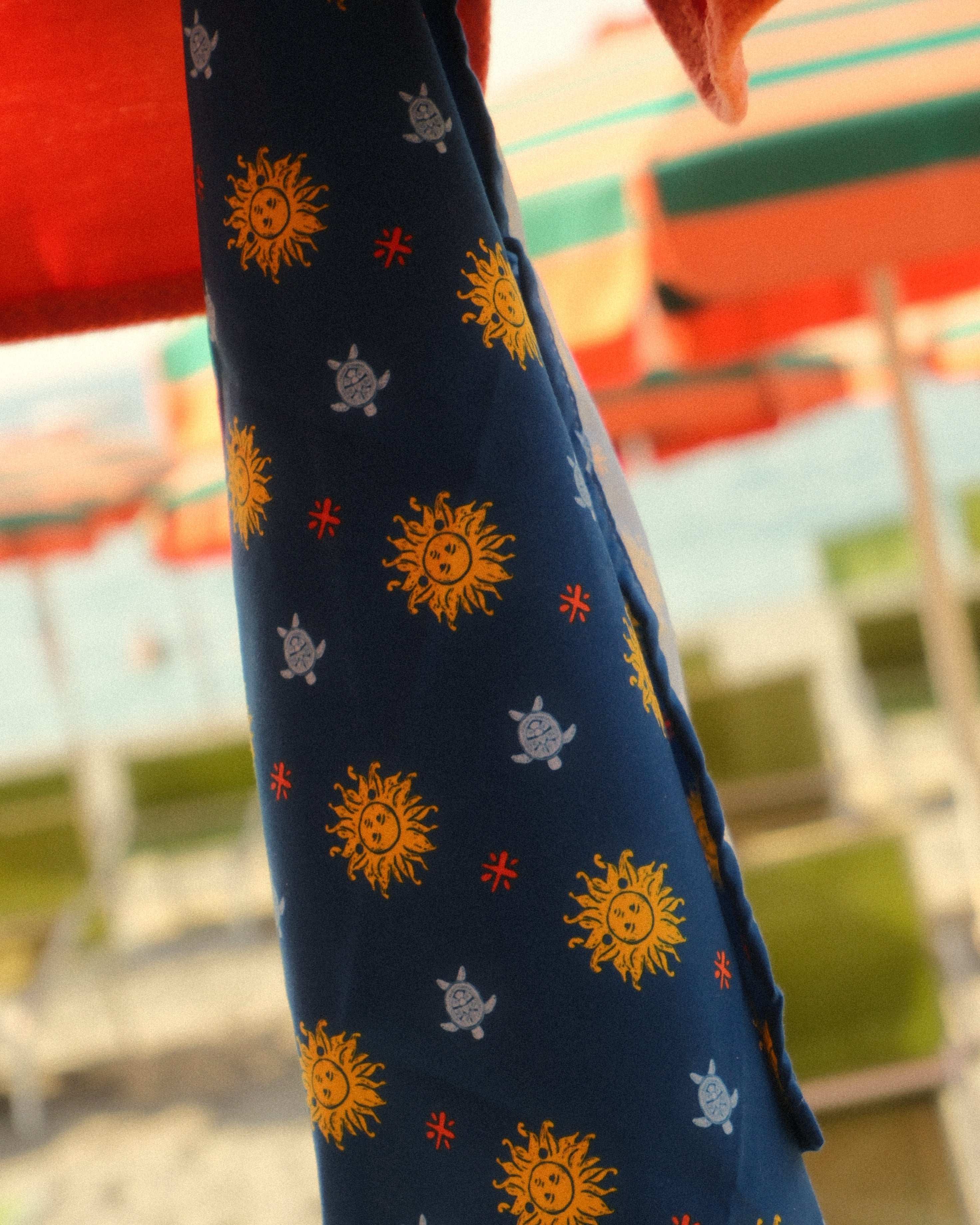 Navy blue fabric with sun and star patterns held by a person against a blurred outdoor background.