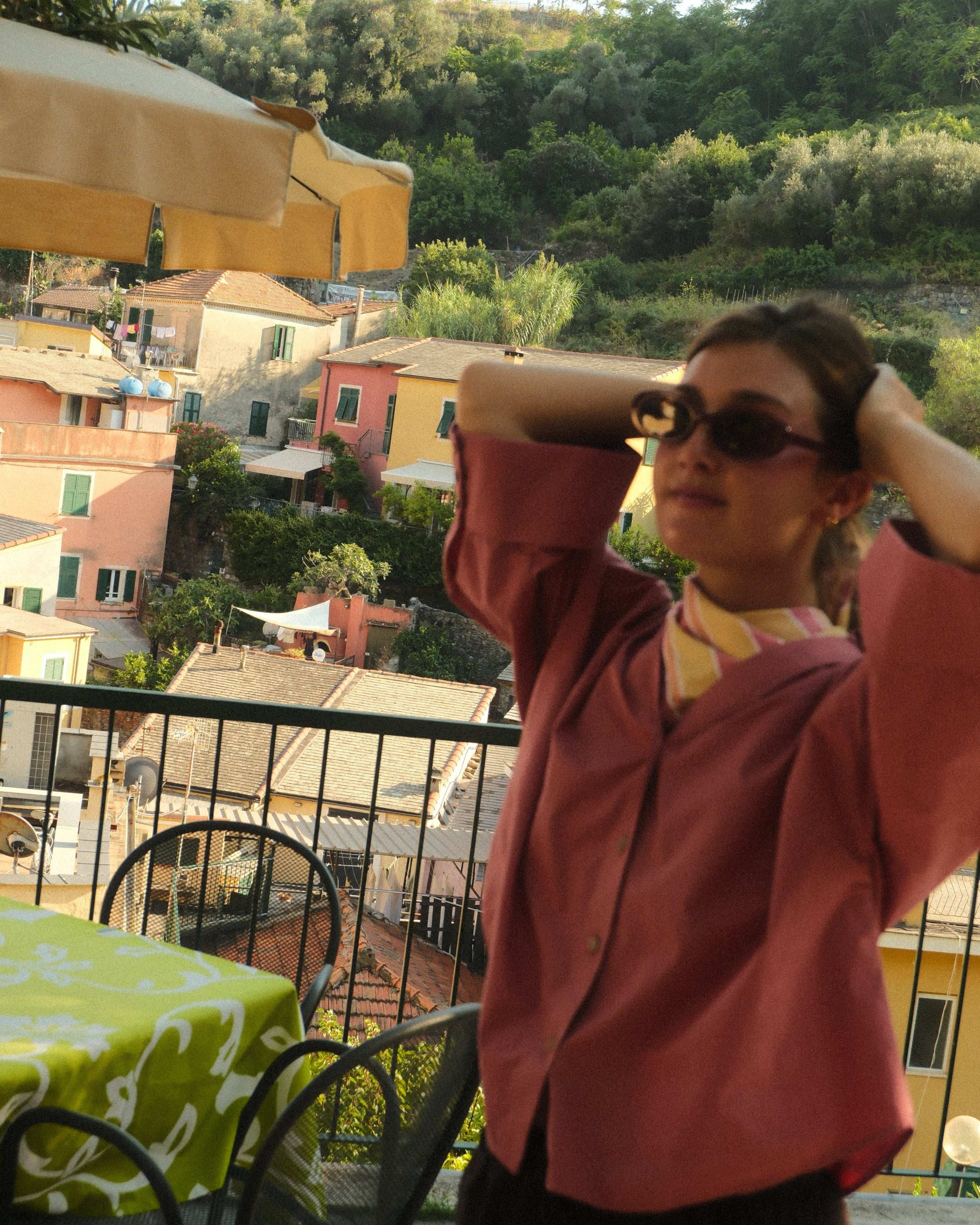 Person wearing a red coat with a scenic background of buildings and trees.
