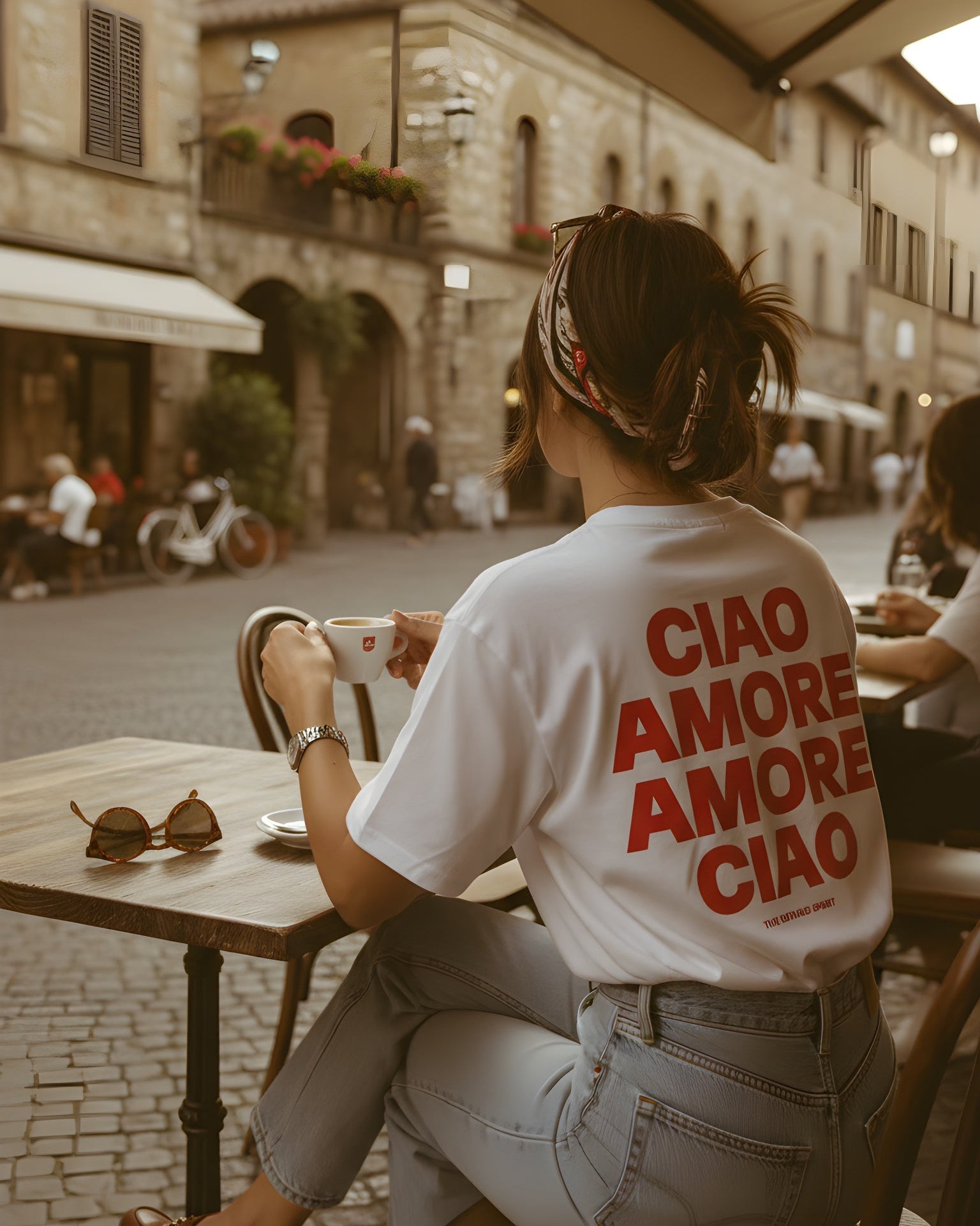 Person sitting at an outdoor cafe with 'CIAO AMORE AMORE CIAO' shirt