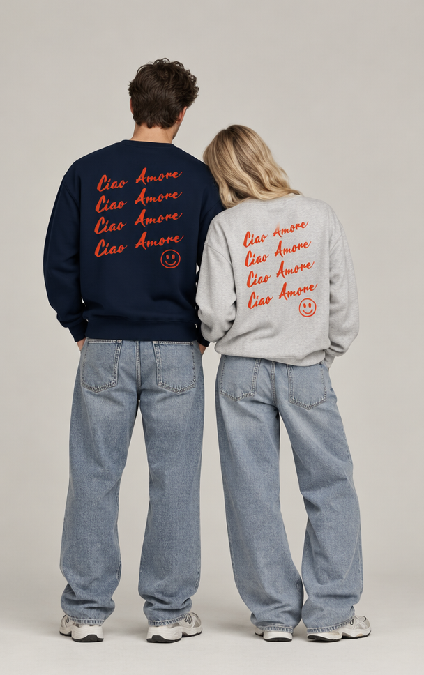 Two models standing side-by-side from behind wearing oversized sweatshirts with 'Ciao Amore' text printed in red on the back. One sweatshirt is navy blue and the other is light gray, paired with wide-leg light-wash jeans.