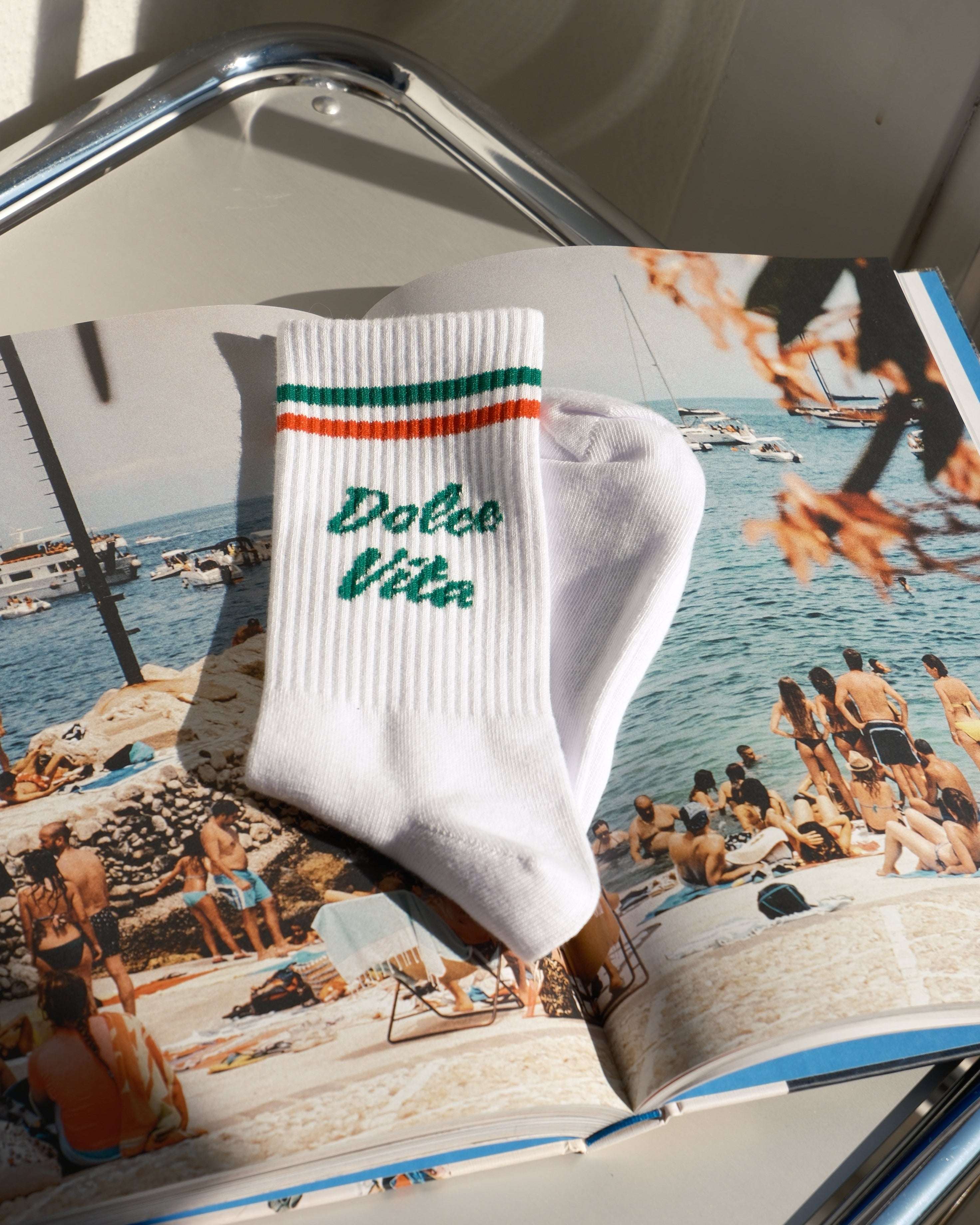 White sock with green text on a magazine with a sailboat and people cover