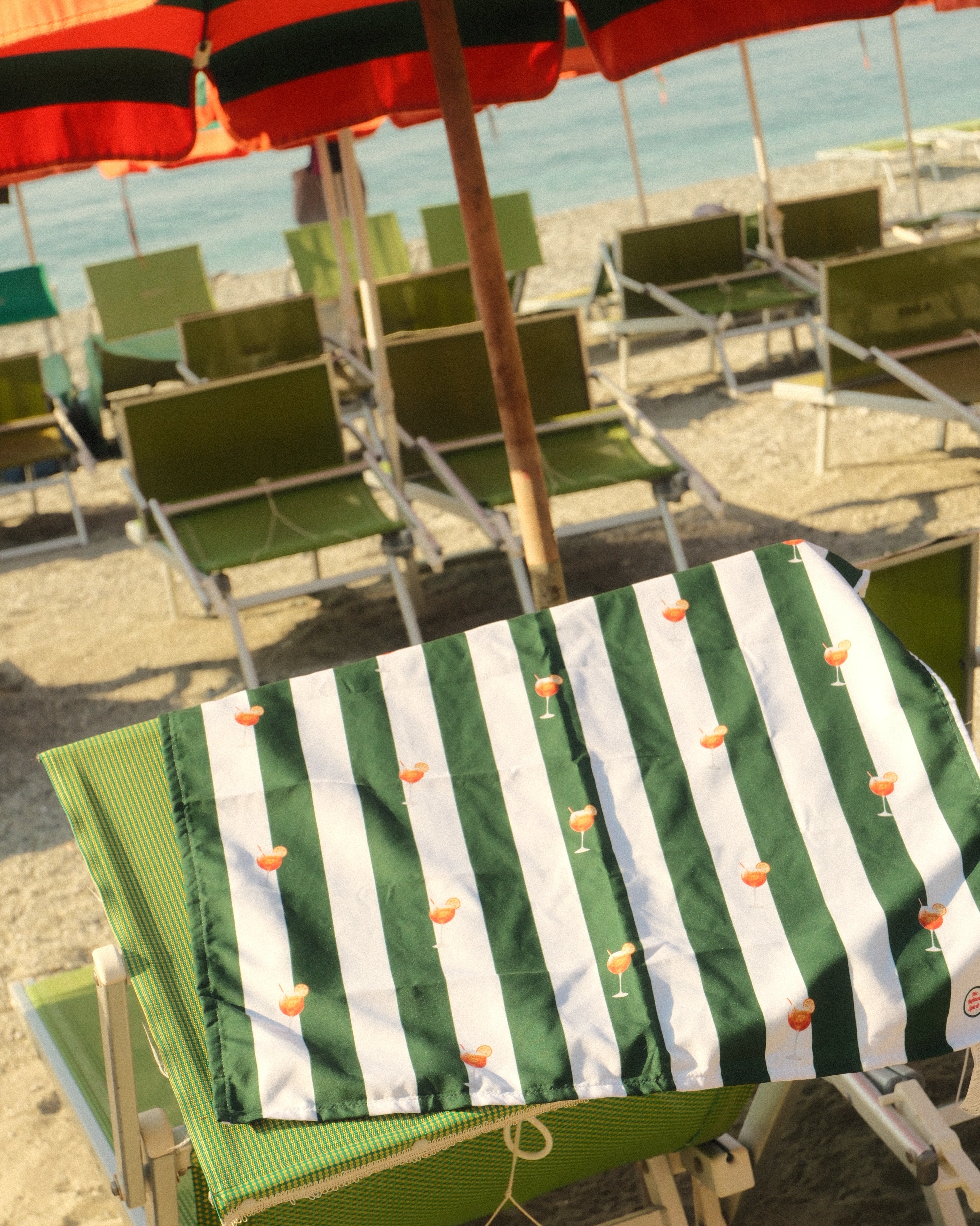 Green and white striped towel on a clothesline with other towels in the background.