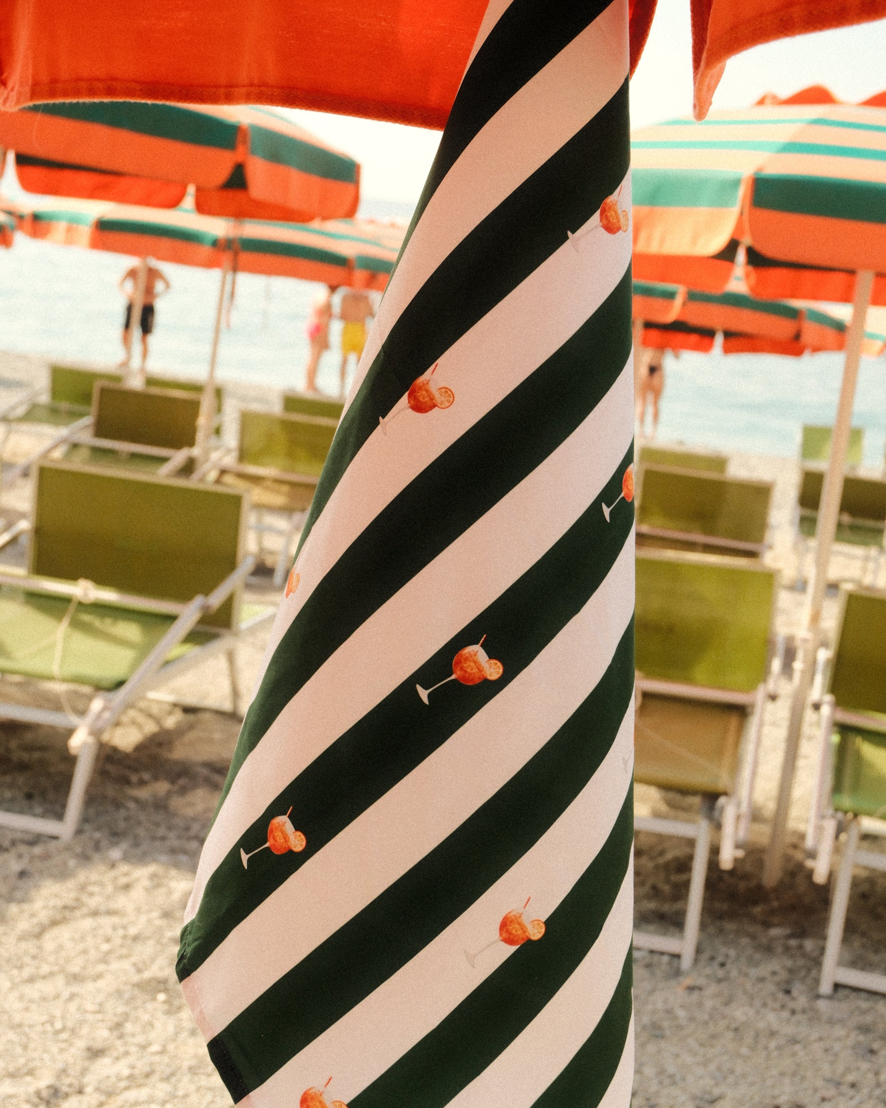 Striped umbrella with green and white stripes on a beach setting