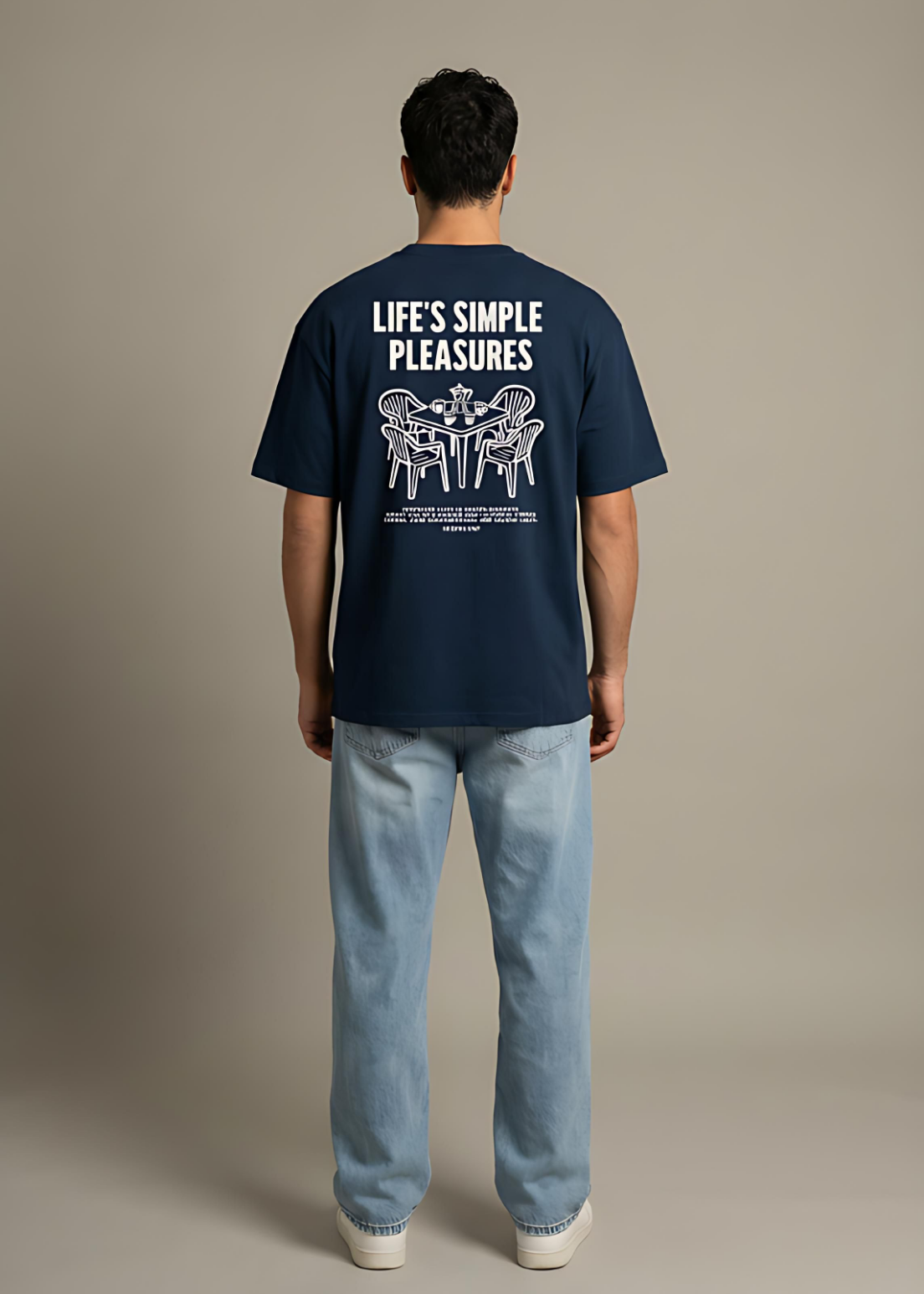Person wearing a navy blue t-shirt with text on the back against a beige background