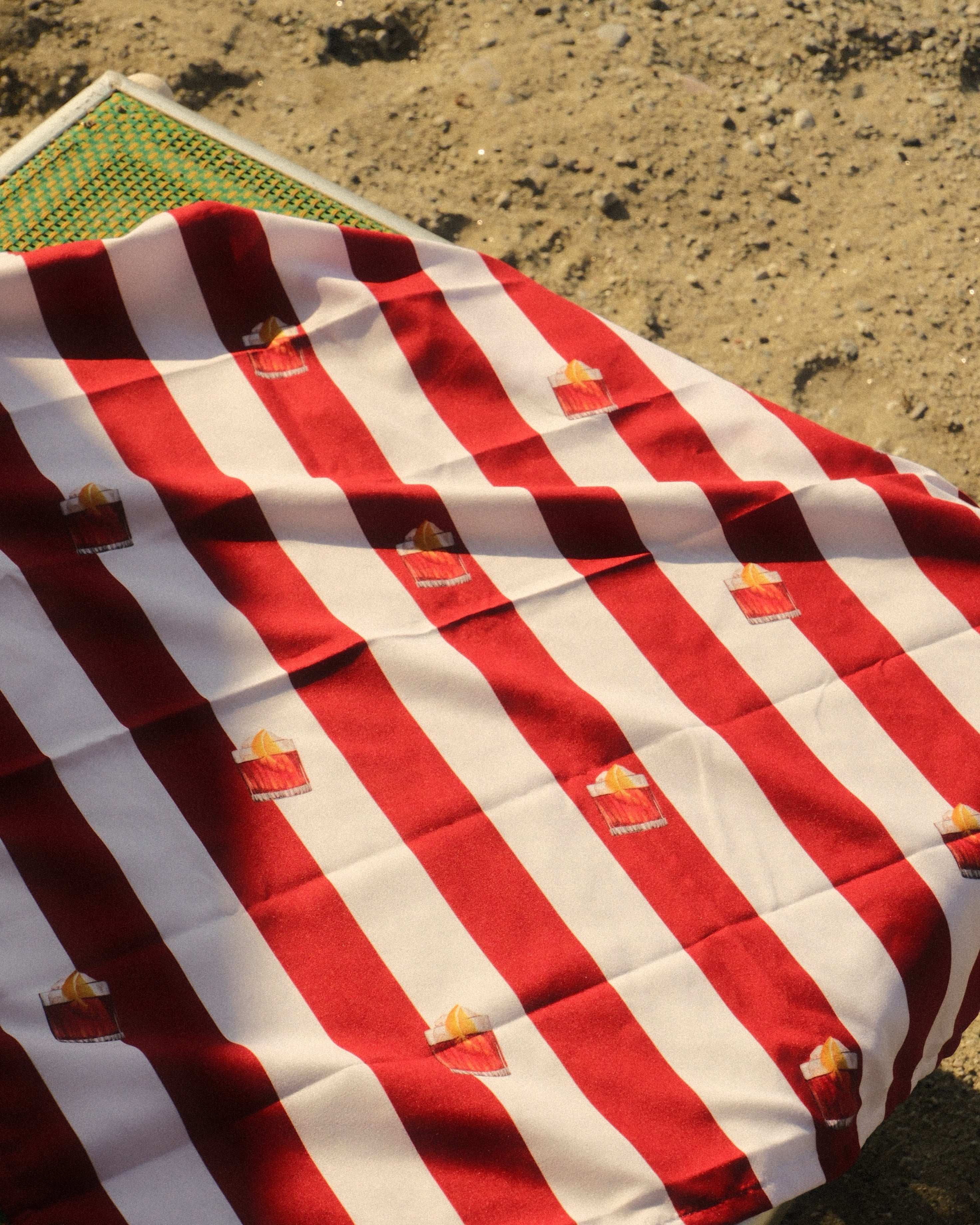 Red and white striped blanket with small orange flowers on a green surface.
