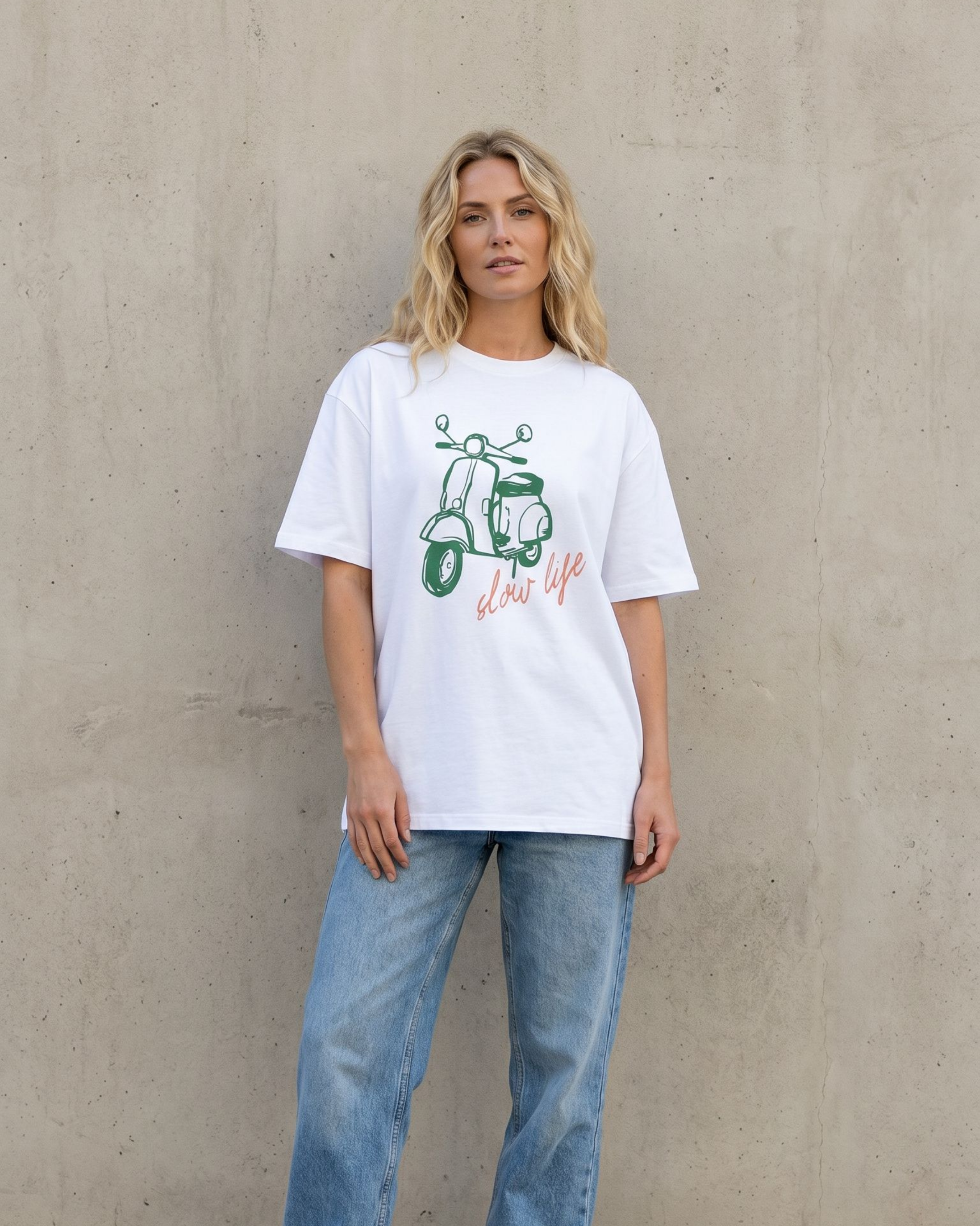 Person wearing a white t-shirt with a graphic design against a plain wall.