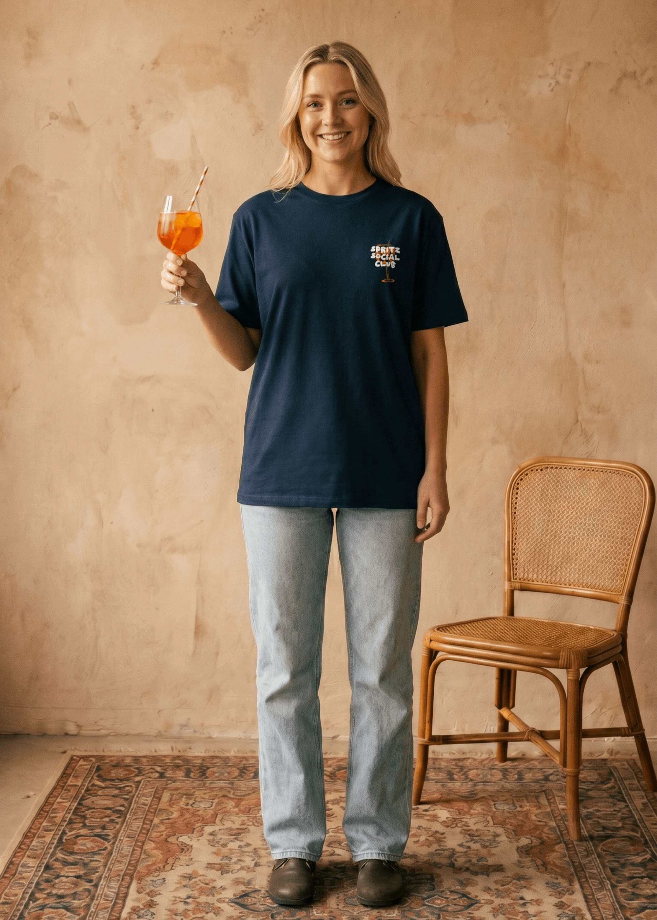 Person holding a drink in a casual setting with a chair and patterned rug.