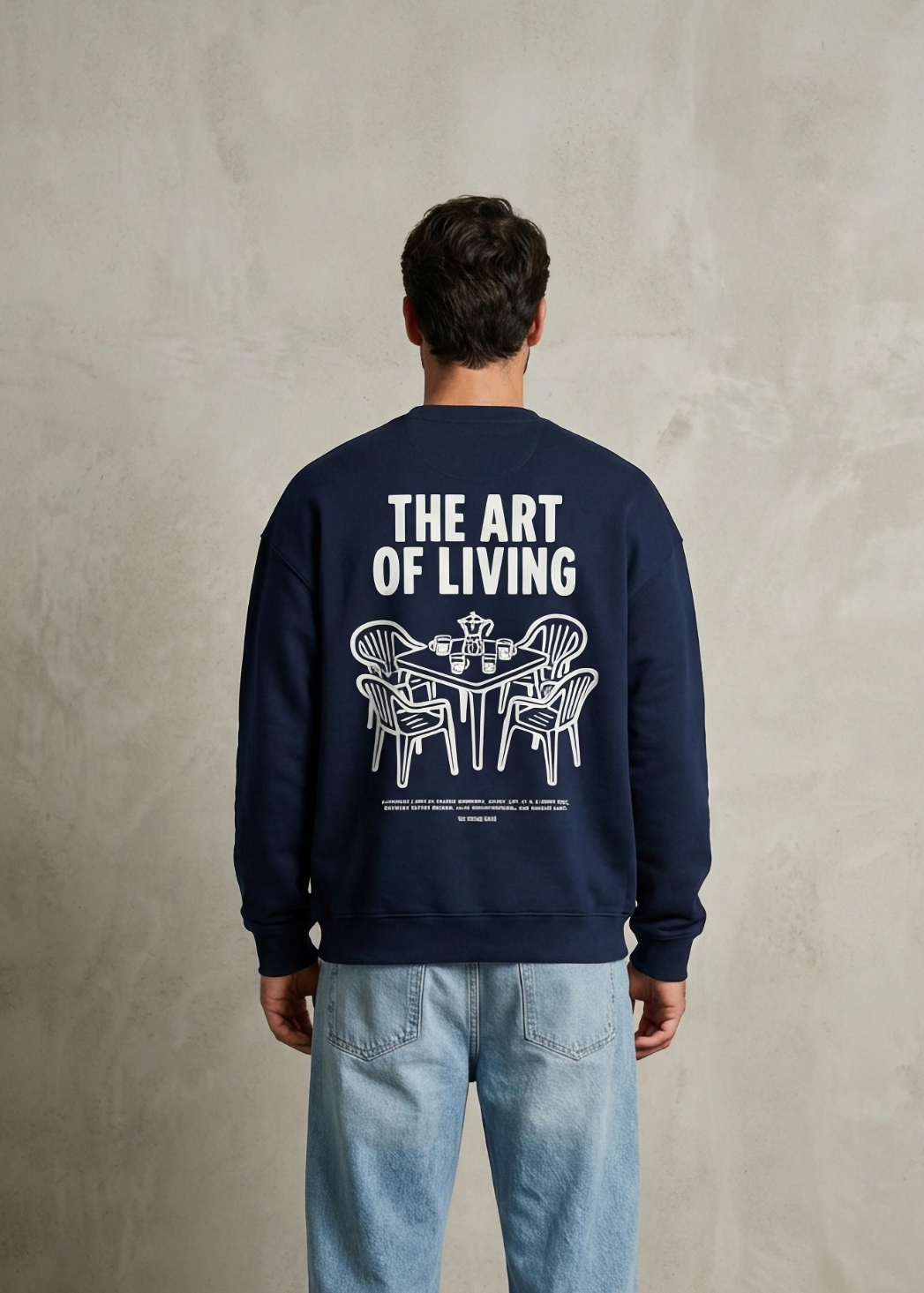 Person wearing a navy blue sweatshirt with 'The Art of Living' text and graphic on the back, standing against a plain background.