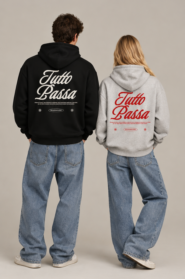 Two models from behind wearing oversized hoodies with 'Tutto Passa' printed on the back, one in black and one in light gray, paired with wide-leg blue jeans, against a neutral studio backdrop.
