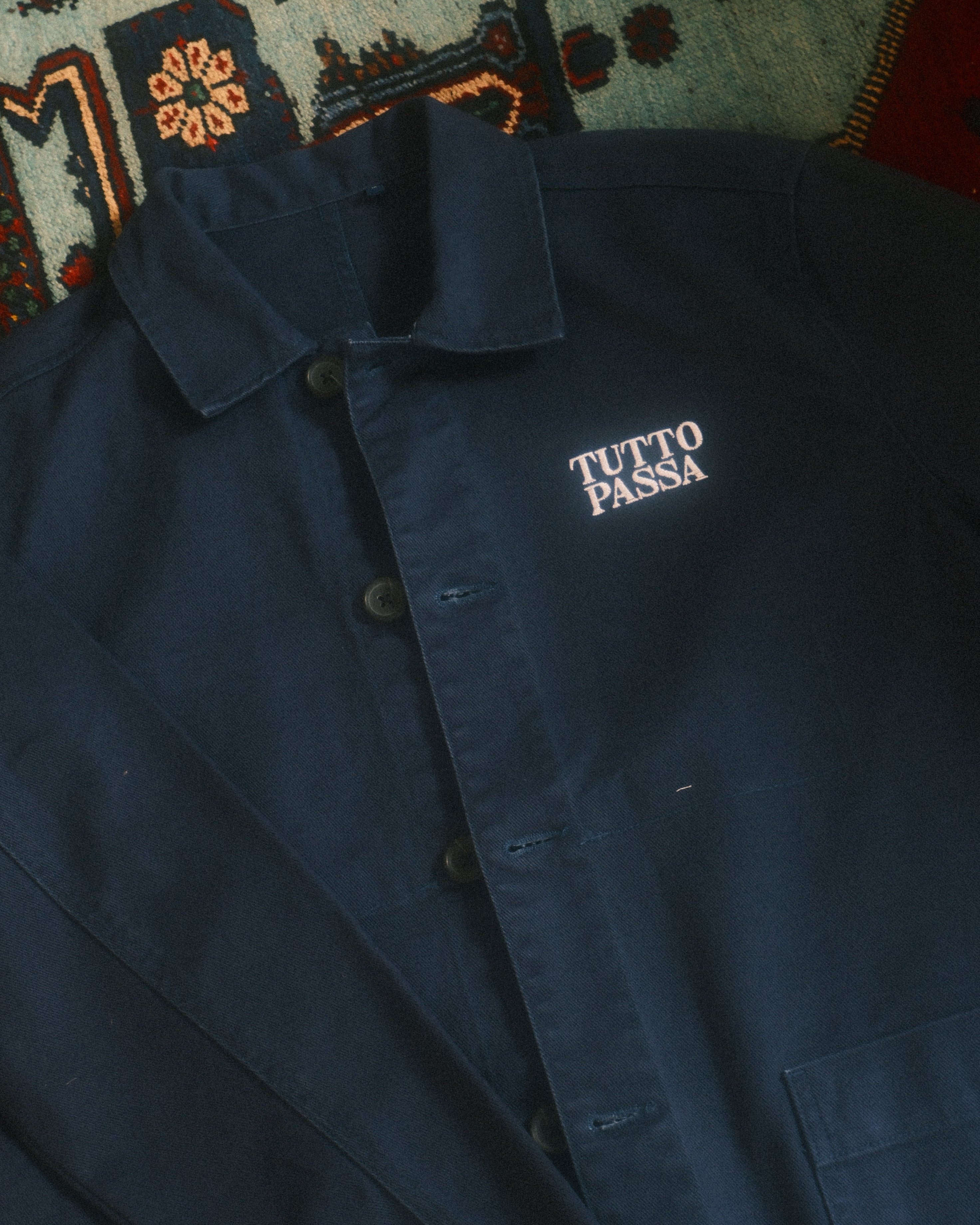 Navy blue jacket with 'Tula Park' logo on a patterned rug