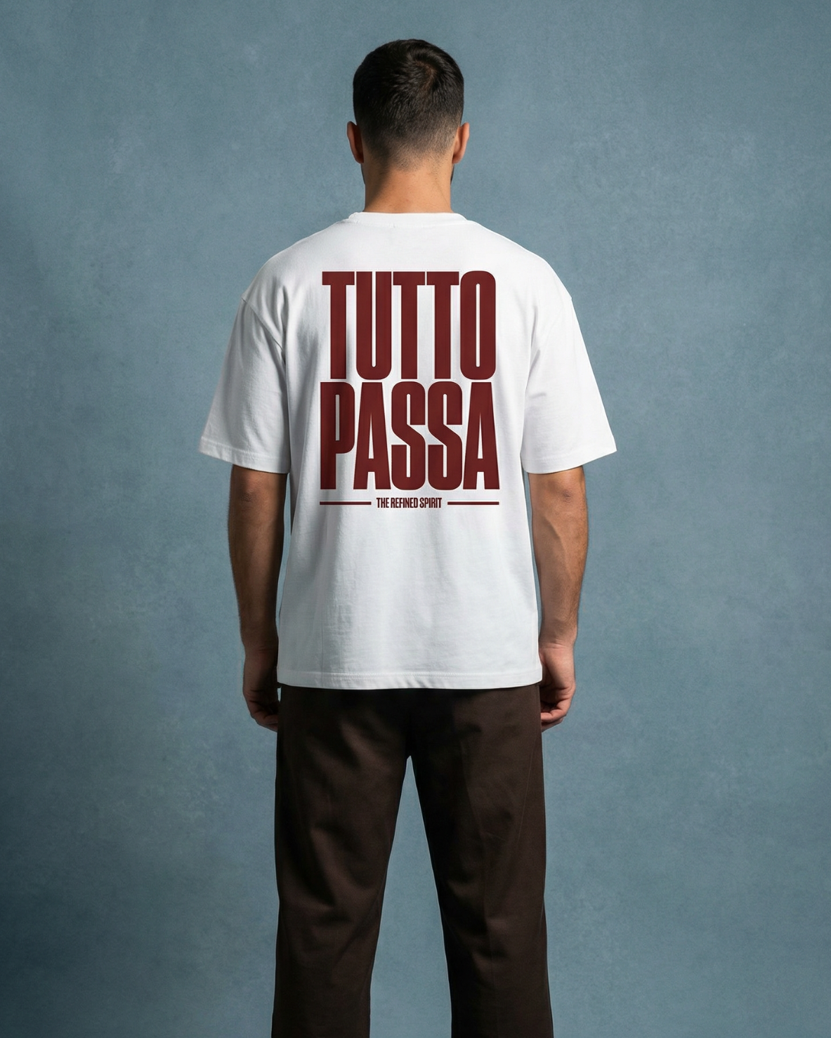 Person wearing a white t-shirt with 'TUTTO PASSA' text on the back against a gray background